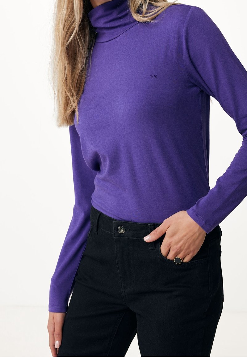 Lila polokragetröja av mjukt tyg, slim fit-design med långa ärmar, kombinerad med svarta högmidjade byxor och en guldaccentring.