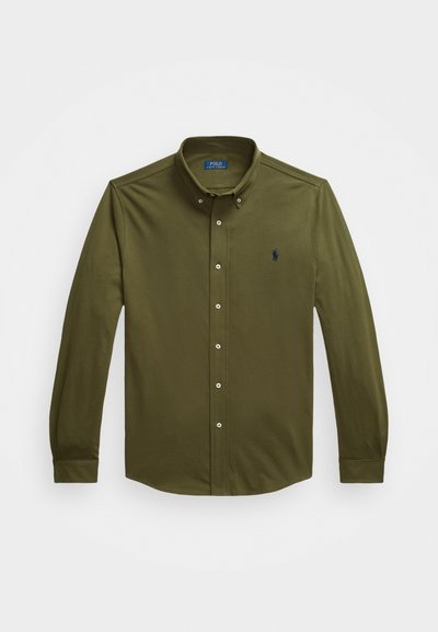 Camisa de manga longa verde oliva com colarinho abotoado, botões brancos e pequeno logótipo bordado no peito. Material em algodão com textura suave.