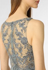 Zijdeachtige jurk met ingewikkelde grijze bloemenborduursels en met kralen versieringen op de achterkant. Ronde halslijn en aansluitende pasvorm.