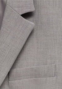 Grau blazer mit strukturiertem Stoff, Reverskragen und einer einzigen Fronttasche. Das Design ist maßgeschneidert mit klaren Linien.