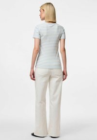 Randig kortärmad skjorta i ljusblått och vitt, figurnära design. I kombination med vita utsvängda jeans. Slät tygtextur.