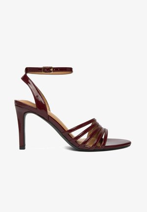 Sandalia de tacón alto en color burdeos con hebilla en el tobillo y múltiples tiras delgadas sobre los dedos, con un acabado brillante.
