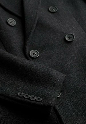 Schwarzer Wollblazer mit Fischgrätenmuster, doppelt geknöpftem Design, fünf schwarzen Knöpfen an den Ärmeln und glatten Revers.