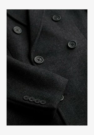 Blazer en laine noir avec une texture en chevrons, design à double boutonnage, cinq boutons noirs aux poignets et revers lisses.