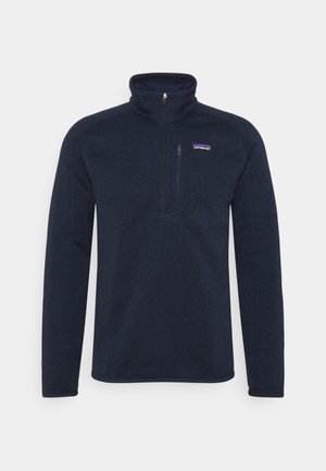 Granatowy polar z długim rękawem,  z zamkiem do ćwiartki i małą kieszenią na piersi na zamek, logo Patagonia na lewej piersi.
