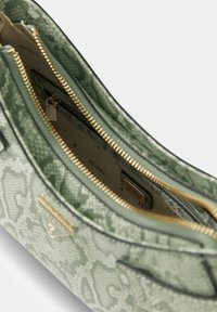 Groene handtas met patroon, voorzien van een gestructureerde afwerking, gouden ritsen en meerdere vakken. Het interieur toont een merklogo op een lichte achtergrond.