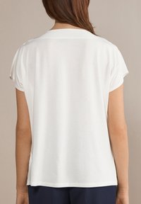 Biały T-shirt z krótkim rękawem i okrągłym dekoltem, o miękkiej, gładkiej fakturze, z luźnym krojem i minimalistycznymi detalami szwów.