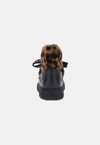 Zapatos de cuero negro con un tacón de piel sintética de leopardo, suela texturizada con detalles en patrón y una correa negra para un ajuste seguro.