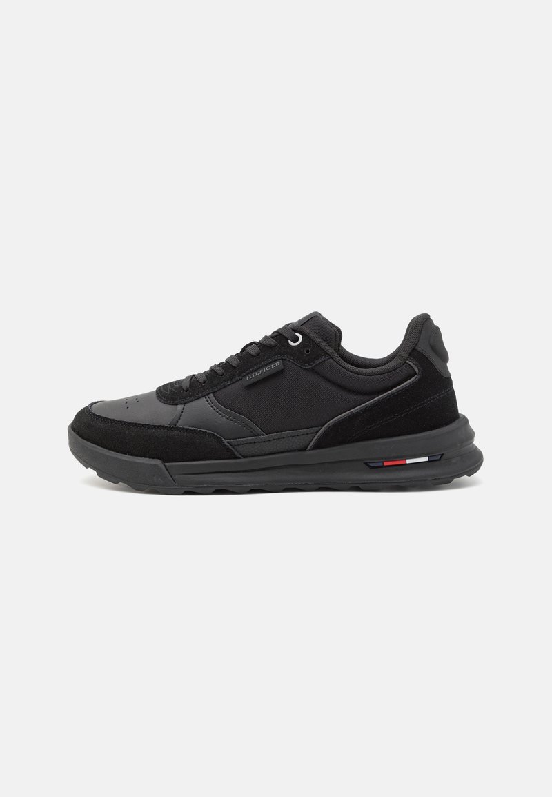 Sneaker nera con una toma in sintetico liscio, dettagli in suede, punta rotonda, chiusura con lacci e suola in gomma texturizzata con dettagli a strisce colorate.