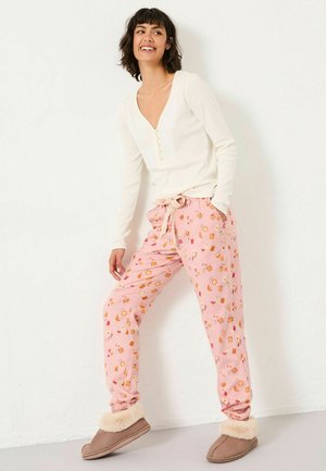White long-sleeve top with button detail, paired with pink patterned pajama pants featuring food motifs, and gray slippers with fur trim.