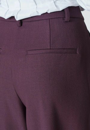 Tumedast burgundi värvi püksid, mis on valmistatud tekstuuriga kangast, sisaldavad kahte tagumist taskut kitsaste klappidega ja on elegantselt lõigetud. Nähtav puhas õmbluse detail.
