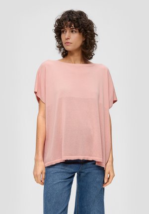 Top en tricot rose clair avec une coupe ample, doté de manches courtes et d'un motif en maille texturé à l'avant. Assorti à un jean bleu.