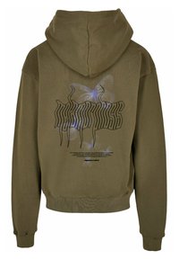 Un hoodie oversize vert olive en tissu doux, arborant un grand motif de papillon et du texte au dos en noir et blanc.
