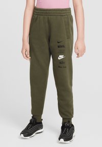 Olive green jogger pants made of soft fabric, featuring an elastic waistband, side pockets, and multiple black Nike logos printed on the front.