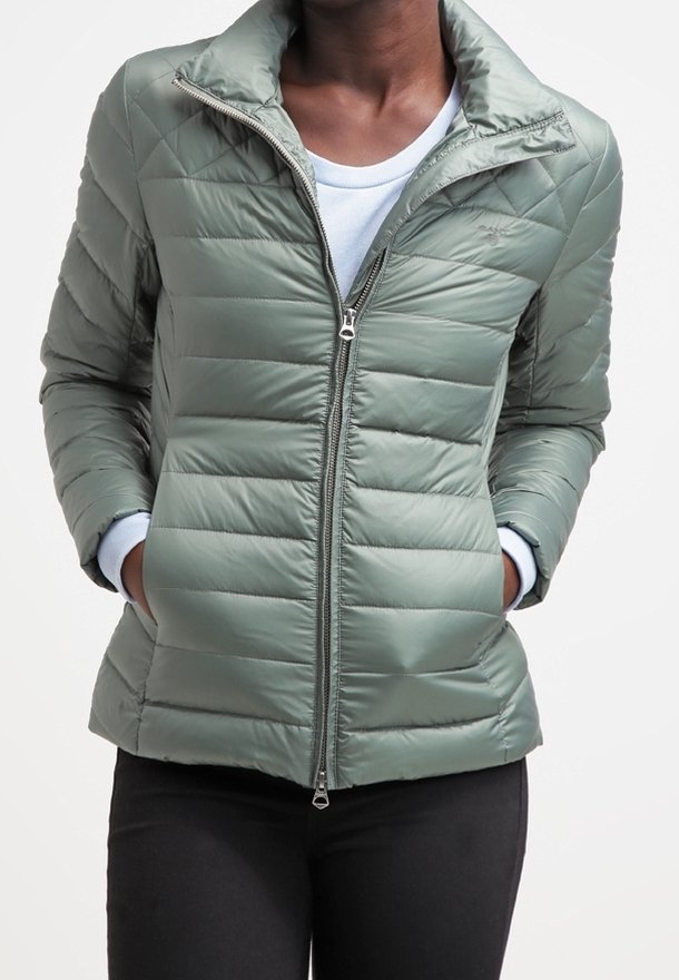 Quiltet puffer jakke i lys grøn med lynlås foran, stående krave og sidelommer. Blødt materiale med en glat tekstur.