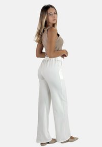 Pantalons larges en satin blanc avec taille élastique, associés à un débardeur côtelé beige. Texture lisse, design minimaliste et coupe décontractée.