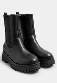 Zwarte enkelboots van glad leer met een dikke, gestructureerde rubberen zool. Voorzien van elastische zijpanelen en een lus aan de achterkant voor gemakkelijk aan- en uittrekken.