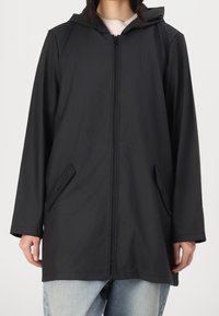 Giacca nera con cappuccio, zip frontale, maniche lunghe e due tasche laterali. Il materiale appare liscio e leggero.
