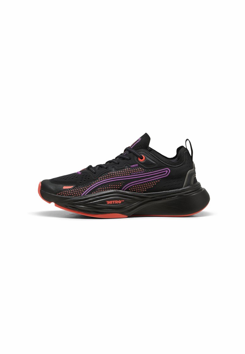 Des chaussures de sport noires avec des accents violets et une tige en mesh texturé. Elles présentent une semelle proéminente avec des détails orange et un motif design.