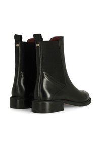 Botas Chelsea de cuero negro con paneles laterales elásticos, diseño de punta redonda y tacón bajo apilado. Textura suave con detalles de costura decorativos.