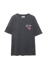 T-shirt en coton noir oversize à manches courtes. Présente un design graphique rose avec du texte et des cerises sur la poitrine gauche. Texture lisse.