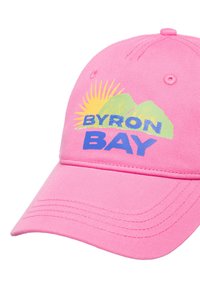 Gorra rosa hecha de algodón con visera curva. Presenta un gráfico multicolor de montañas y el texto "BYRON BAY". El texto es negrita y prominente.