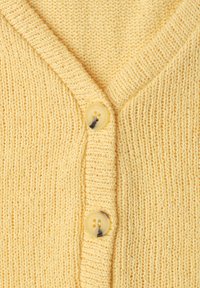 Gros plan d'un cardigan jaune en tricot avec deux boutons beiges et un col en V côtelé.