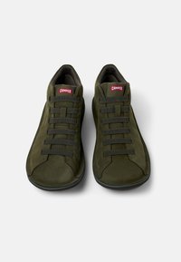 Scarpe verdi in suede con lacci elasticizzati, punta arrotondata e supporto per la caviglia imbottito. Presentano un logo rosso del marchio sulla linguetta. Nessun motivo visibile.
