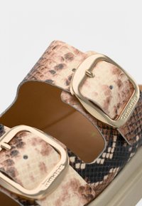 Sandales à imprimé serpent marron et noir avec deux boucles dorées, semelle plate et surface texturée. Conçues pour être portées à bout ouvert.