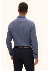 Camicia da uomo blu scuro con maniche lunghe, bottoni e colletto, in tessuto testurizzato, abbinata a pantaloni scuri.