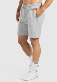 Pantalones cortos deportivos grises con cinturilla elástica, cordón y bolsillos laterales, que presentan una textura suave y un ajuste relajado.