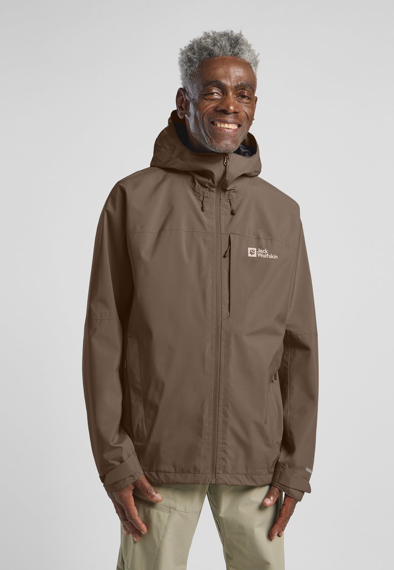 Giubbotto impermeabile marrone con cappuccio, dotato di tasca anteriore con zip e loghi. Texture liscia, design aderente, adatto per uso all'aperto.