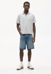 Tricou polo gri deschis, pantaloni scurți din denim, șosete albe și adidași. Croi lejer, cu mâneci scurte și guler clasic. Textură de denim albastru.