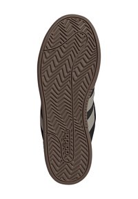 Sohle eines braunen Adidas-Schuhs mit Zickzack-Profil und Logo, das in der Nähe des Fersenbereichs geprägt ist.