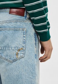 Ανοιχτό μπλε τζιν με χαλαρή εφαρμογή, με καφέ δερμάτινη ετικέτα και κεντημένο λογότυπο "Pepe Jeans" στην πίσω τσέπη.