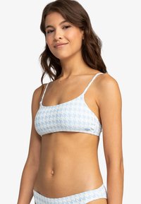Sujetador de bikini con patrón de espiga azul y blanco, con tirantes finos y una textura suave, que presenta un acento de logo azul claro en el lateral.