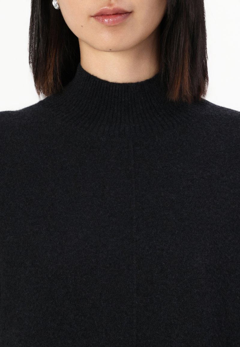 Schwarzer Strickpullover mit Rollkragen, gerippter Textur und hohem Kragen, mit glatter oberfläche und minimaler Detailierung.