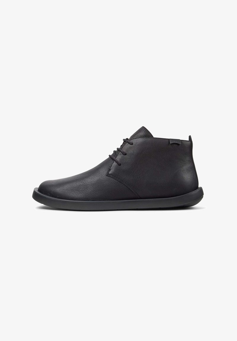Botas de cuero negro hasta el tobillo con un acabado suave, suela de goma plana y diseño minimalista. Presentan costuras sutiles y cierre con cordones.