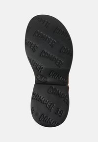 Svart gummisul med präglad "CAMPER"-logotyp och storlek "38". Texturerad yta för grepp, med subtila varumärkesdetaljer.