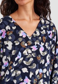 Top navy a V con un motivo floreale nei colori bianco, rosa, verde e blu, con un tessuto texturizzato e maniche a vestibilità rilassata.