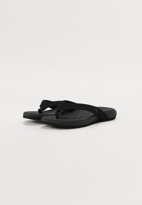 Black flip-flops with a textured footbed, fabric straps, and a minimalist design. Rubber sole for durability and comfort.