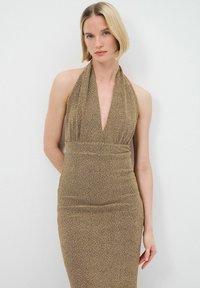 Robe à col halter en tissu métallique doré, silhouette ajustée avec un décolleté en V profond, taille froncée et finition lisse et texturée.