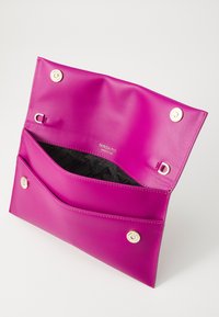 Fuchsia läderväska med två fack, magnetiska knäppningar och ett svart mönstrat inre med varumärkeslogotyp. Slät textur.