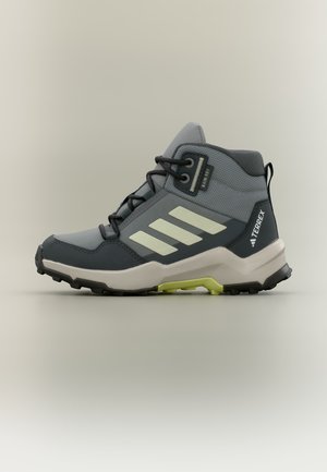 Botte de randonnée Adidas Terrex grise et noire avec des accents et lacets vert clair, logo latéral et semelle robuste.