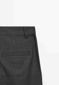 Close-up of dark gray pinstripe formal trousers showing back pocket and belt loop on a white background.