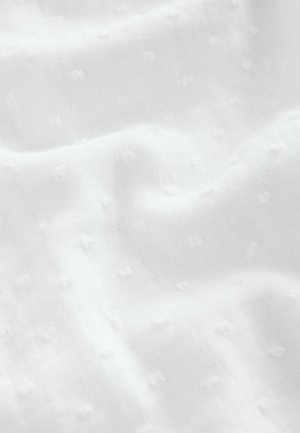 Tissu blanc avec un motif texturé de petits points surélevés. Le matériau semble léger et légèrement transparent avec un drapé doux.