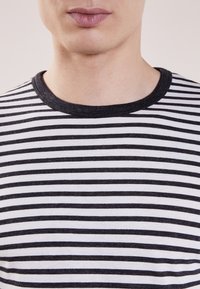 Randig t-shirt med svart och vita horisontella ränder, rund halsringning, blandning av bomull, mjuk textur och avslappnad design.