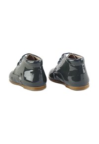 Zapatos de charol gris oscuro con puntera redonda, diseño con cordones y costuras sutiles. Textura suave y suela de goma baja.