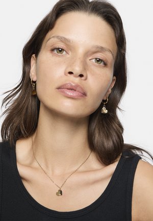 Gold-tone earrings with heart-shaped charms and a chain link, paired with a matching gold-tone necklace featuring a geometric pendant.