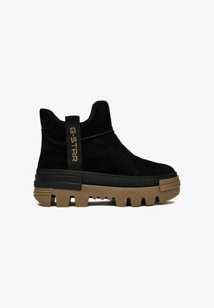 Černá kotníková bota z semiše s tlustou hnědou podrážkou s výrazným vzorkem, poutko s nápisem "G-STAR" a postranní zapínání na zip.